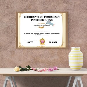 Op de afbeelding: Een certificaat van bekwaamheid in microblading, met een gouden lijst en een roze lint. De tekst luidt "CERTIFICAAT VAN BEKWAAMHEID IN MICROBLADING wordt met trots uitgereikt aan: Ter ere van uw consistente beheersing van de kunst van microblading op deze dag DATUM TRAINER"