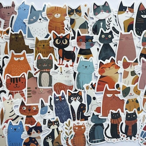 May include: A sheet of colorful cat stickers with various poses and designs. The stickers feature cats in different colors, including orange, black, white, brown, and gray. Some cats are wearing hats or scarves.