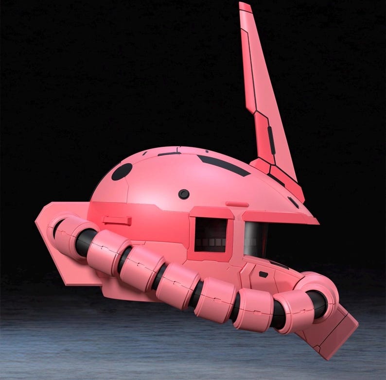 Op de afbeelding: Een roze robotkop met een hoge vin en een cilindrische arm. De kop heeft een afgeronde bovenkant met zwarte details en een rechthoekig venster. Het ontwerp suggereert een futuristisch of sciencefiction thema.