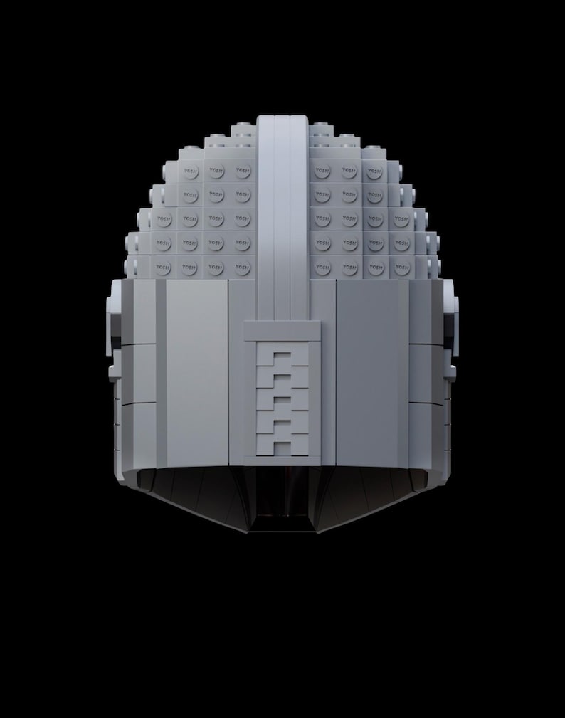 May include: A gray helmet constructed from interlocking toy bricks, set against a black background. The helmet features a rounded top and a rectangular visor area. The design is symmetrical, with a central vertical ridge.