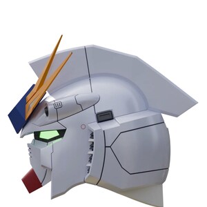 May include: A side profile of a white robot head with orange and blue accents. The robot head has a red mouth, green eyes, and a detailed design with black lines. The head is a stylized representation of a Gundam.