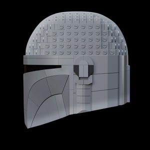 May include: A gray Mandalorian helmet constructed from interlocking toy bricks. The helmet features a curved visor and a segmented design, with a dark visor area. The helmet is set against a black background.