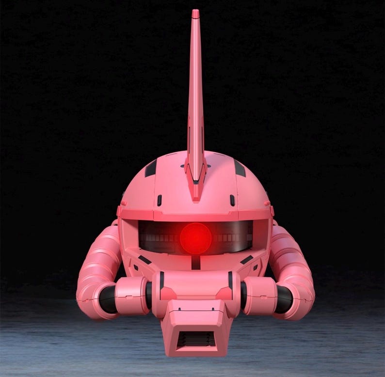 Op de afbeelding: Een roze robothoofd met een opvallende antenne en een gloeiend rood oog. De kop heeft een afgeronde vorm met zwarte accenten en buisvormige structuren aan de zijkanten. De achtergrond is donker en effen.