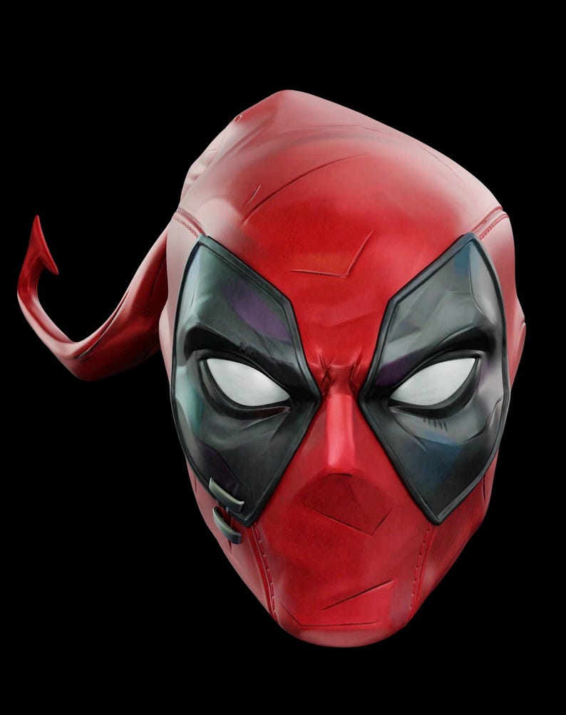 May include: A red and black Deadpool mask with white eyes and a distinctive headpiece. The mask has a textured surface and is set against a black background. The mask is a replica of the character's mask.