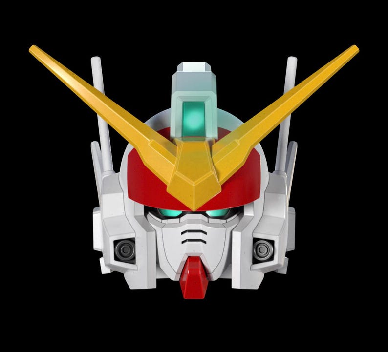 May include: A close-up of a Gundam robot head, featuring a white face with red and yellow accents. The robot has a red helmet, yellow V-fins, and green eyes. The background is solid black.