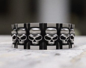 May include: A silver ring with a repeating pattern of skull designs.