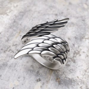 Handcrafted silver wing ring displaying dimensional feather work and spiritual symbolism