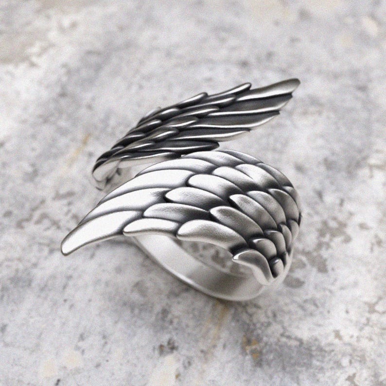 Handcrafted silver wing ring displaying dimensional feather work and spiritual symbolism