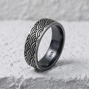 May include: A silver ring with a repeating wave pattern design. The ring is made of 925 silver and has a dark, oxidized finish. The ring is a size 9.