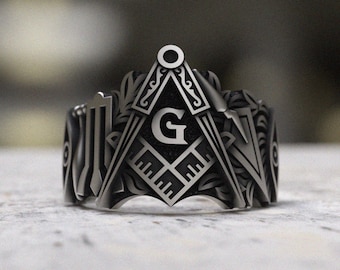May include: A silver ring with a detailed design featuring a Masonic compass and square with the letter "G" in the center.
