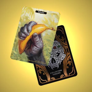 May include: Two collectible cards. One card features a detailed illustration of a gorilla's hand holding a banana, with the word "BANANA" at the top. The other card has a skull design and the words "COLLECTOR TOKENS".