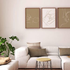 May include: Three framed line art prints depicting a person receiving a massage. The prints are in brown frames and have a beige background. The prints are hung on a white wall above a white couch with brown throw pillows.