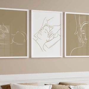 May include: Three minimalist line art prints in white frames on a beige wall. Each print features a line drawing of a person receiving a massage.