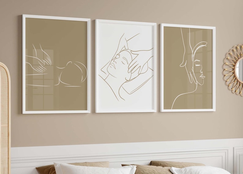 May include: Three minimalist line art prints in white frames on a beige wall. Each print features a line drawing of a person receiving a massage.