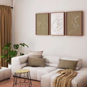 May include: A white sectional sofa with brown throw pillows and a brown blanket. Three framed line drawings of people receiving a massage hang on the wall above the sofa.
