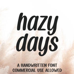 May include: A digital graphic featuring the black text hazy days in a bold, handwritten script font. Below this, smaller black text reads A HANDWRITTEN FONT COMMERCIAL USE ALLOWED. The background consists of soft, beige, feathery pampas grass.