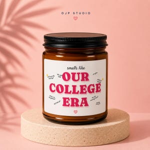 Peut inclure: Un pot de bougie en verre brun avec un couvercle noir et une étiquette blanche. L'étiquette porte le texte "smells like OUR COLLEGE ERA" en rose et noir, entouré de petites phrases manuscrites et d'étoiles jaunes, avec un petit cœur rose en bas.
