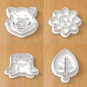 Op de afbeelding: Een set van vier witte plastic koekjesvormen met een varkenskop, een lachende bloem, een boomstronk met een gezicht en een gekarteld blad. Elke vorm heeft een opstaande rand voor het snijden van deeg en interne details voor afdrukken.