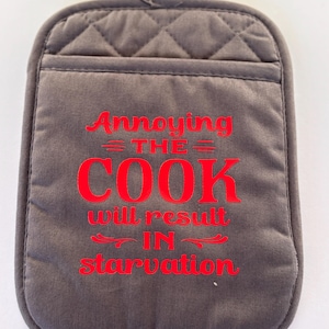 May include: A gray quilted oven mitt with a pocket and a loop for hanging. The mitt features the red text "Annoying the Cook will result in starvation."