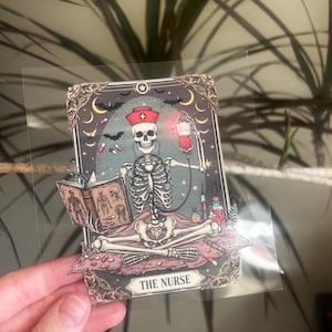 May include: A tarot card illustration featuring a skeleton in a nurse's cap and stethoscope, holding a blood bag and a medical textbook. The card has a dark, gothic aesthetic with bats, moons, and the text "THE NURSE".