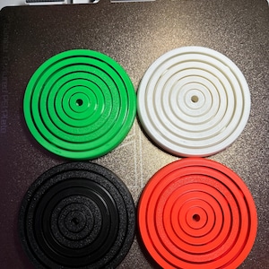 May include: Four circular, concentric ring designs in different colors. The rings are green, white, black, and orange.