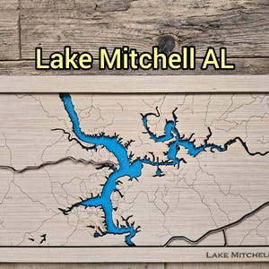 Könnte beinhalten: Lasergeschnittene Holzkarte des Lake Mitchell, AL, mit einem blau mit Epoxidharz gefüllten See und Details des umliegenden Landes. Die Karte ist gerahmt und trägt den Text "Lake Mitchell AL" oben und unten.
