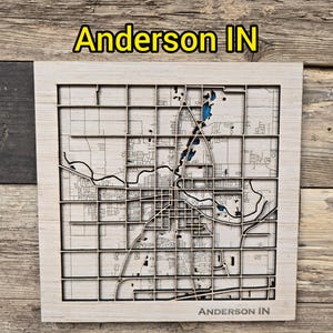 May include: A wooden map of Anderson, IN, with a layered design. The map features a grid pattern and detailed streets, with the city name at the top and bottom. The background is a wooden surface.