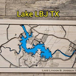 May include: A wooden map of Lake LBJ in Texas, with the lake in bright blue and the surrounding land in natural wood tones. The text "Lake LBJ TX" is at the top, and "LAKE LYNDON B. JOHNSON TX" is at the bottom.
