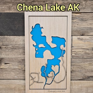 May include: Wooden framed artwork featuring a detailed map of Chena Lake, AK, with a vibrant blue lake cutout. The text "Chena Lake AK" is displayed at the top and bottom of the frame. The artwork is set against a rustic wooden background.
