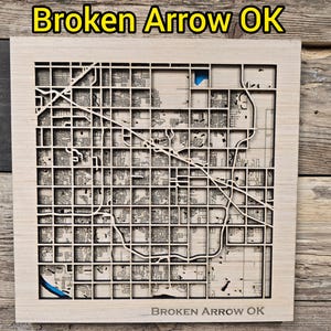 Puede incluir: Mapa de madera cortado con láser de Broken Arrow, OK, con el diseño detallado de la ciudad. El mapa está sobre un fondo de madera, con el texto "Broken Arrow OK" en la parte superior e inferior. El mapa es de color madera clara.