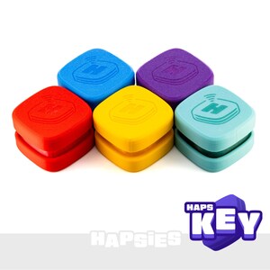 May include: Five square-shaped silicone covers in red, blue, yellow, purple, and light blue, each featuring an embossed letter H with a signal icon. The text HAPSIES and HAPS KEY is displayed in the lower right corner of the image.