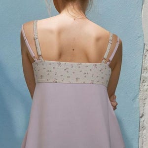 May include: A light purple sleeveless top with a floral print on the bodice and a flowy skirt. The top has thin straps and a relaxed fit.