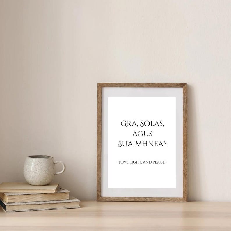 May include: A framed print with the text "GR&Aacute;, SOLAS, AGUS SUAIMHNEAS" in black lettering on a white background. The text is in Irish Gaelic and translates to "Love, Light, and Peace".