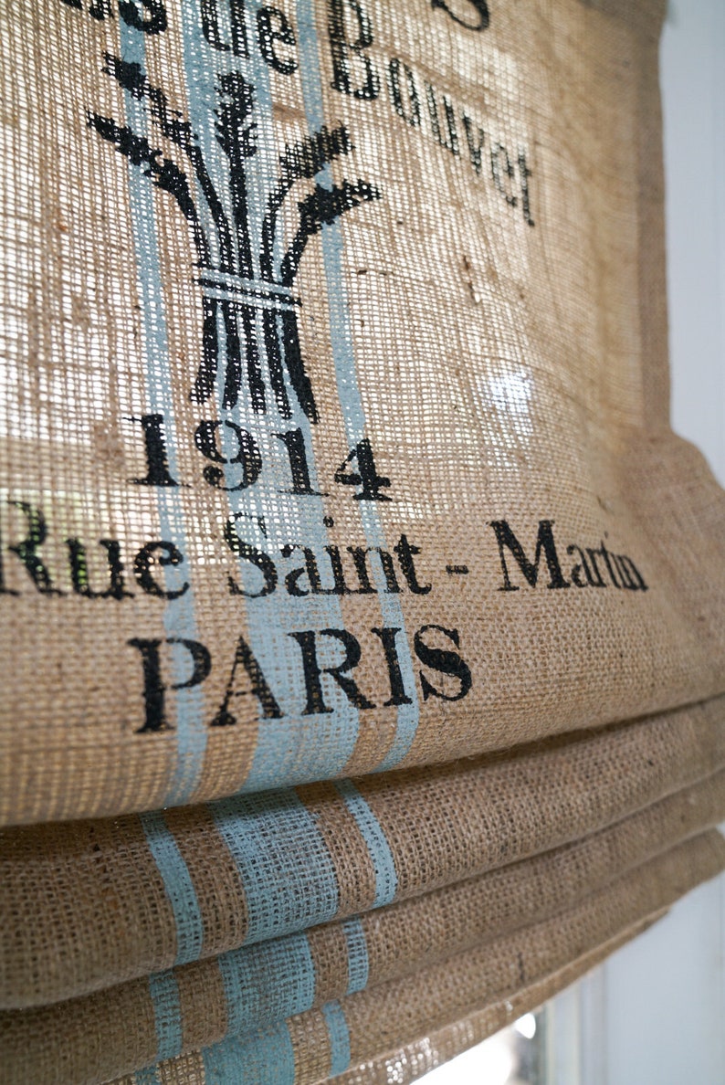 May include: A brown burlap roman shade with blue stripes and black text that reads "1914 Rue Saint-Martin PARIS".