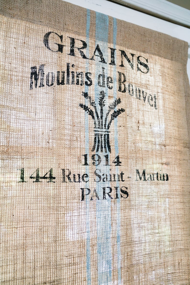 May include: A burlap sack with blue stripes and black text that reads "GRAINS Moulins de Bouvet 1914 144 Rue Saint-Martin PARIS".