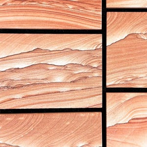 May include: A collection of rectangular stone tiles featuring a natural, swirling pattern of light peach, tan, and deep terracotta bands. The tiles are arranged in a grid pattern with thin, dark black grout lines separating each individual stone piece.