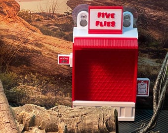 May include: A red and white plastic toy replica of a fast food restaurant with the words "Five Flies" on the sign. The toy has suction cups on the back to attach to a surface.