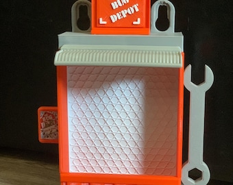 May include: A red and gray toy building with a sign that says "The Bug Depot". The building has a white grid pattern on the front and a gray wrench on the side.