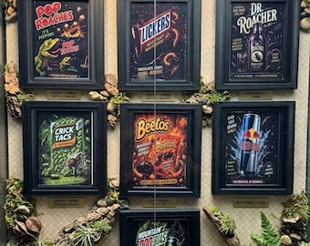 May include: A display of framed novelty art prints featuring humorous reptile-themed snacks and drinks. The collection includes "Pop Roaches," "Lickers," "Dr. Roacher," "Crick Tacs," "Beetos," "Red Bug," and "Mountain Doo-Bias."
