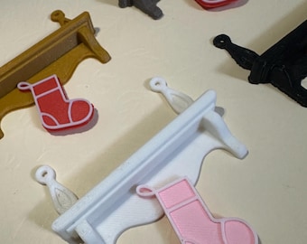 May include: A collection of miniature shelves in various colors, including gold, gray, white, and black. Each shelf has a decorative design and is paired with a small Christmas stocking in red or pink. The items are likely for holiday decor.