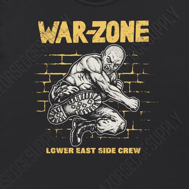 Peut inclure: T-shirt noir avec un graphisme vieilli repr&eacute;sentant une figure muscl&eacute;e et chauve en position de combat. Le texte "WAR-ZONE" est au-dessus de la figure, et "LOWER EAST SIDE CREW" en dessous, en jaune. Le fond est un mur de briques.