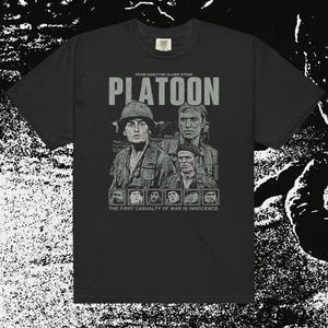 May include: Black t-shirt featuring a graphic from the movie "Platoon." The design includes the film's title, the director's name, and images of soldiers. The phrase "The First Casualty of War is Innocence" is printed below the images.