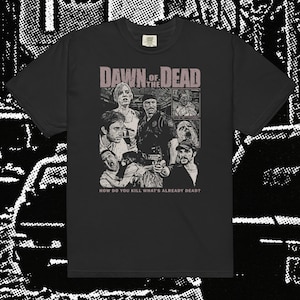 May include: Black t-shirt featuring a graphic from the movie "Dawn of the Dead." The design includes the movie title and images of characters. The text "HOW DO YOU KILL WHAT'S ALREADY DEAD?" is printed below the images. The shirt has a crew neck.
