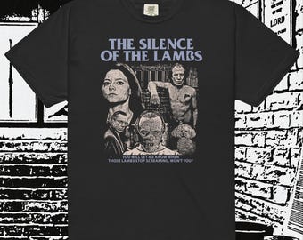 May include: Black t-shirt with a graphic from the film "The Silence of the Lambs". The design includes the film's title, character portraits, and the quote "You will let me know when those lambs stop screaming, won't you?"