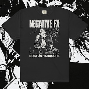 May include: Black t-shirt featuring a monochrome graphic of a singer with a microphone. The text "NEGATIVE FX" is above the image, and "BOSTON HARDCORE" is below. The shirt has a crew neck and short sleeves.