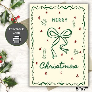 Könnte beinhalten: Cremefarbene Weihnachtskarte mit grünem Rand, Schleife und Text. Die Karte zeigt die Worte "MERRY Christmas" in grüner Schrift, zusammen mit kleinen roten Sternen, Lebkuchenmännern und Kerzenillustrationen. Die Karte misst 12,7 cm x 17,8 cm.