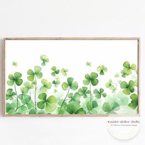 Könnte beinhalten: Ein gerahmter Aquarelldruck mit einem Feld aus grünen Kleeblättern. Das Kunstwerk zeigt verschiedene Grüntöne mit detaillierten Blättern und Stängeln vor einem weißen Hintergrund. Der Rahmen ist hellbraun.