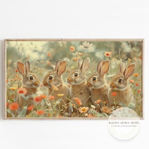 Könnte beinhalten: Gerahmter Druck mit fünf braunen Kaninchen in einem Feld mit Wildblumen. Das Kunstwerk hat eine weiche, Vintage-Ästhetik mit warmen Tönen von Orange, Grün und Beige. Der Text "wonder atelier studio" befindet sich unten rechts.