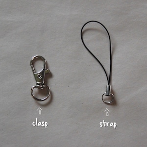 May include: A silver-colored metal clasp and a black strap with a metal ring. The word "clasp" is written below the clasp, and the word "strap" is written below the strap.