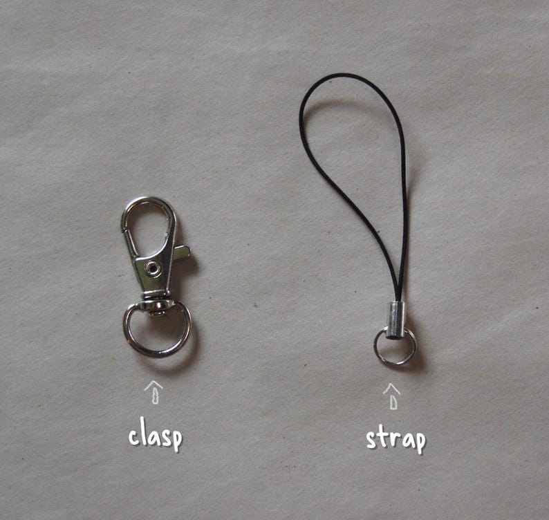 May include: A silver-colored metal clasp and a black strap with a metal ring. The word "clasp" is written below the clasp, and the word "strap" is written below the strap.